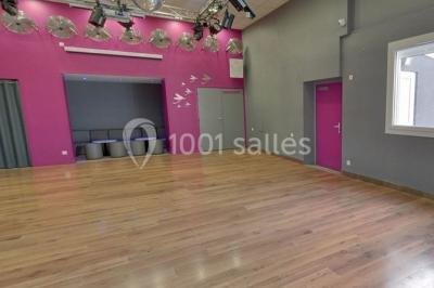 Salle de danse vide avec éclairage coloré, boules à facettes suspendues et reflets lumineux sur les murs.