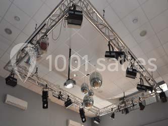 Salle de danse vide avec éclairage coloré, boules à facettes suspendues et reflets lumineux sur les murs.