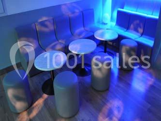 Salle de danse vide avec éclairage coloré, boules à facettes suspendues et reflets lumineux sur les murs.