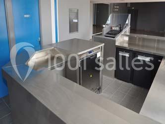 Cuisine professionnelle avec plans de travail en inox, lave-vaisselle encastré et équipements de rangement.