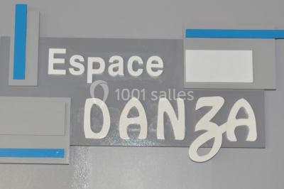 Salle de danse vide avec éclairage coloré, boules à facettes suspendues et reflets lumineux sur les murs.