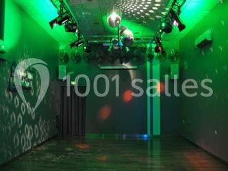 Salle de danse vide avec éclairage coloré, boules à facettes suspendues et reflets lumineux sur les murs.