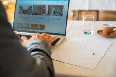 Repas avec poisson, burger, vin et eau servis sur une table en terrasse avec vue sur la mer.