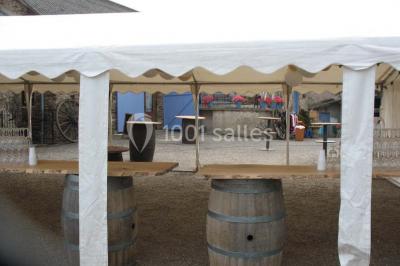 Tables décorées de nappes blanches, ornées de bougies entourées de fleurs, dans un cadre extérieur fleuri.
