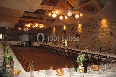 Tables décorées de nappes blanches, ornées de bougies entourées de fleurs, dans un cadre extérieur fleuri.