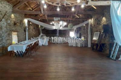 Tables décorées de nappes blanches, ornées de bougies entourées de fleurs, dans un cadre extérieur fleuri.