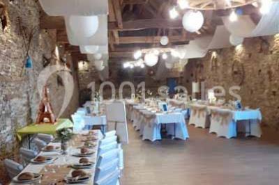 Tables décorées de nappes blanches, ornées de bougies entourées de fleurs, dans un cadre extérieur fleuri.