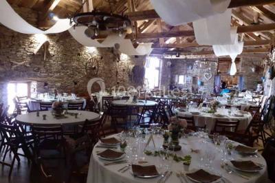 Tables décorées de nappes blanches, ornées de bougies entourées de fleurs, dans un cadre extérieur fleuri.