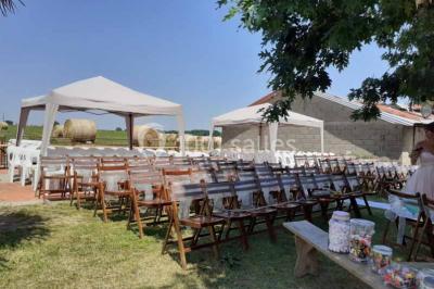 Tables décorées de nappes blanches, ornées de bougies entourées de fleurs, dans un cadre extérieur fleuri.