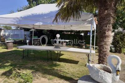 Tables décorées de nappes blanches, ornées de bougies entourées de fleurs, dans un cadre extérieur fleuri.