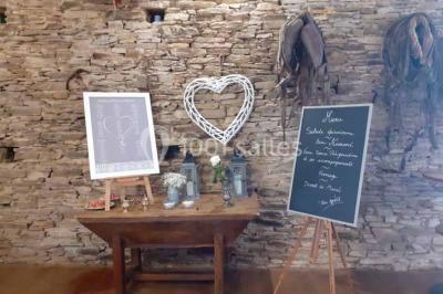Tables décorées de nappes blanches, ornées de bougies entourées de fleurs, dans un cadre extérieur fleuri.
