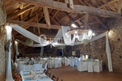 Tables décorées de nappes blanches, ornées de bougies entourées de fleurs, dans un cadre extérieur fleuri.
