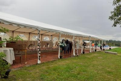 Tables décorées de nappes blanches, ornées de bougies entourées de fleurs, dans un cadre extérieur fleuri.
