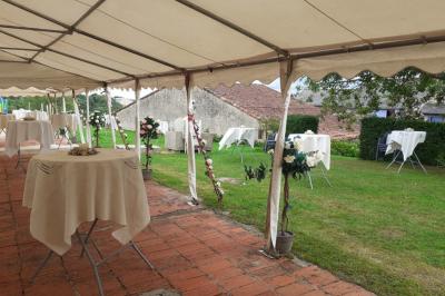 Tables décorées de nappes blanches, ornées de bougies entourées de fleurs, dans un cadre extérieur fleuri.