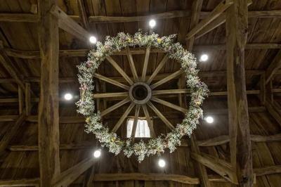 Tables décorées de nappes blanches, ornées de bougies entourées de fleurs, dans un cadre extérieur fleuri.