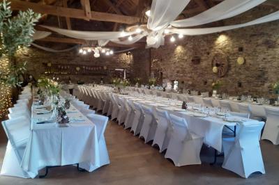 Tables décorées de nappes blanches, ornées de bougies entourées de fleurs, dans un cadre extérieur fleuri.