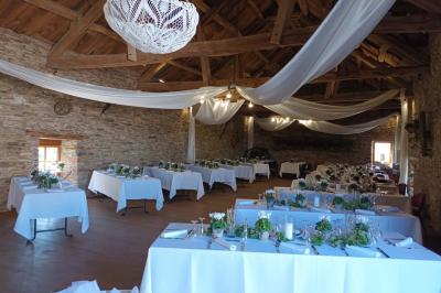 Tables décorées de nappes blanches, ornées de bougies entourées de fleurs, dans un cadre extérieur fleuri.