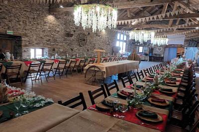 Tables décorées de nappes blanches, ornées de bougies entourées de fleurs, dans un cadre extérieur fleuri.