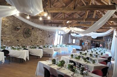 Tables décorées de nappes blanches, ornées de bougies entourées de fleurs, dans un cadre extérieur fleuri.