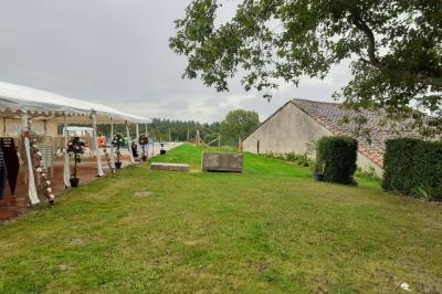 Tables décorées de nappes blanches, ornées de bougies entourées de fleurs, dans un cadre extérieur fleuri.