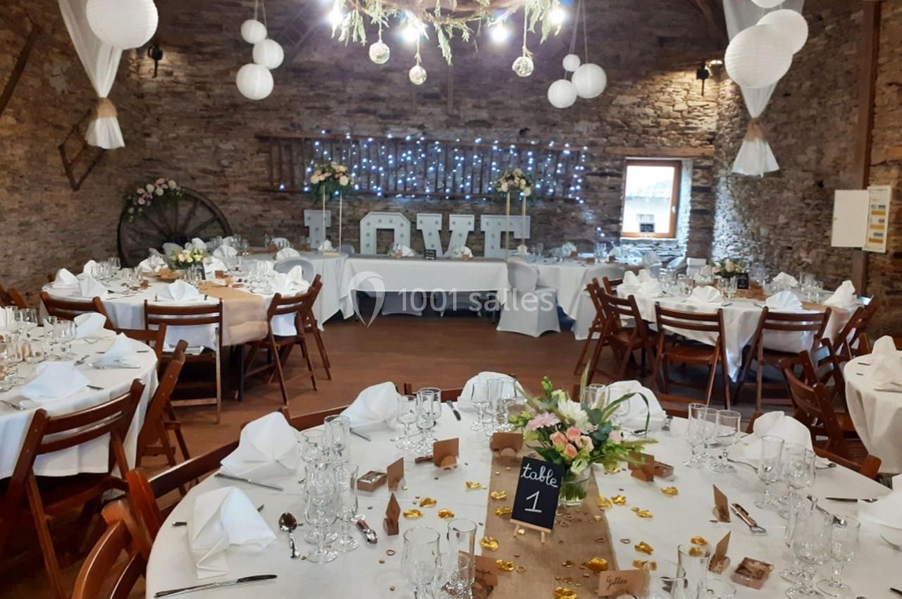 Salle de réception décorée pour un mariage, avec tables dressées, guirlandes lumineuses et le mot ’LOVE’ en arrière-plan.