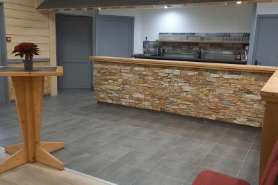 Paysage rural avec une ferme traditionnelle entourée de champs verdoyants et d'arbres sous un ciel nuageux.