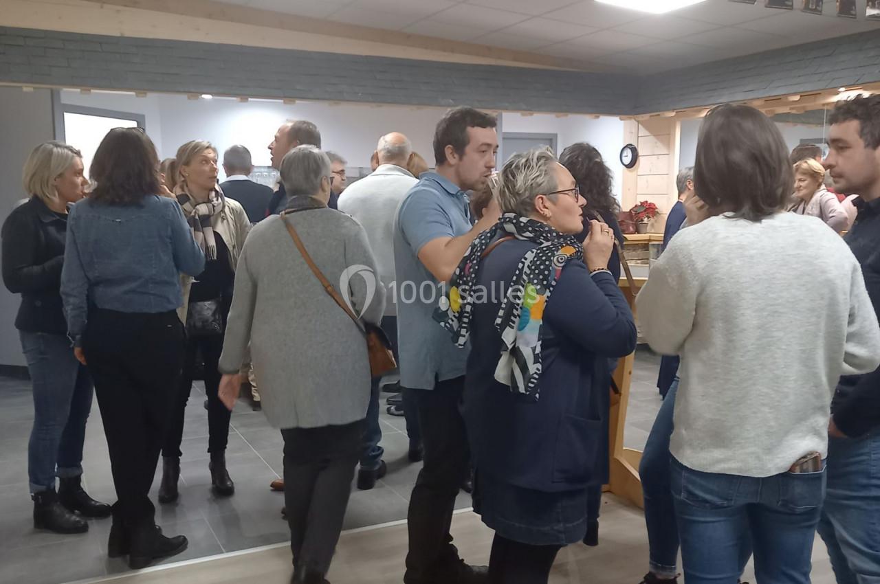 Un groupe de personnes discute dans une salle lumineuse avec un plafond décoré de petites affiches.