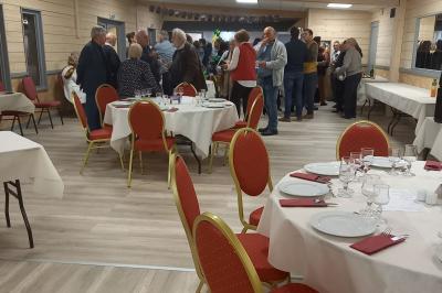 Paysage rural avec une ferme traditionnelle entourée de champs verdoyants et d'arbres sous un ciel nuageux.