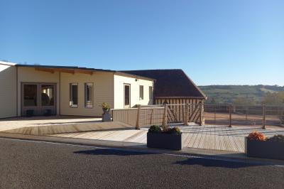 Paysage rural avec une ferme traditionnelle entourée de champs verdoyants et d'arbres sous un ciel nuageux.