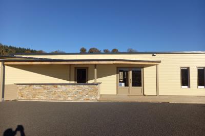 Paysage rural avec une ferme traditionnelle entourée de champs verdoyants et d'arbres sous un ciel nuageux.