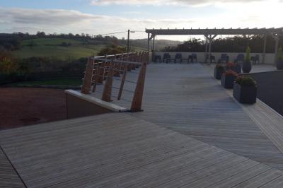 Paysage rural avec une ferme traditionnelle entourée de champs verdoyants et d'arbres sous un ciel nuageux.