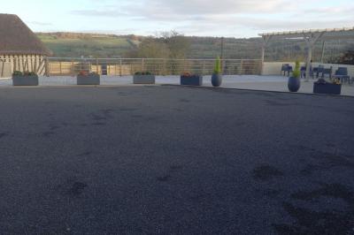 Paysage rural avec une ferme traditionnelle entourée de champs verdoyants et d'arbres sous un ciel nuageux.