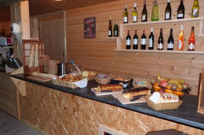 Paysage rural avec une ferme traditionnelle entourée de champs verdoyants et d'arbres sous un ciel nuageux.
