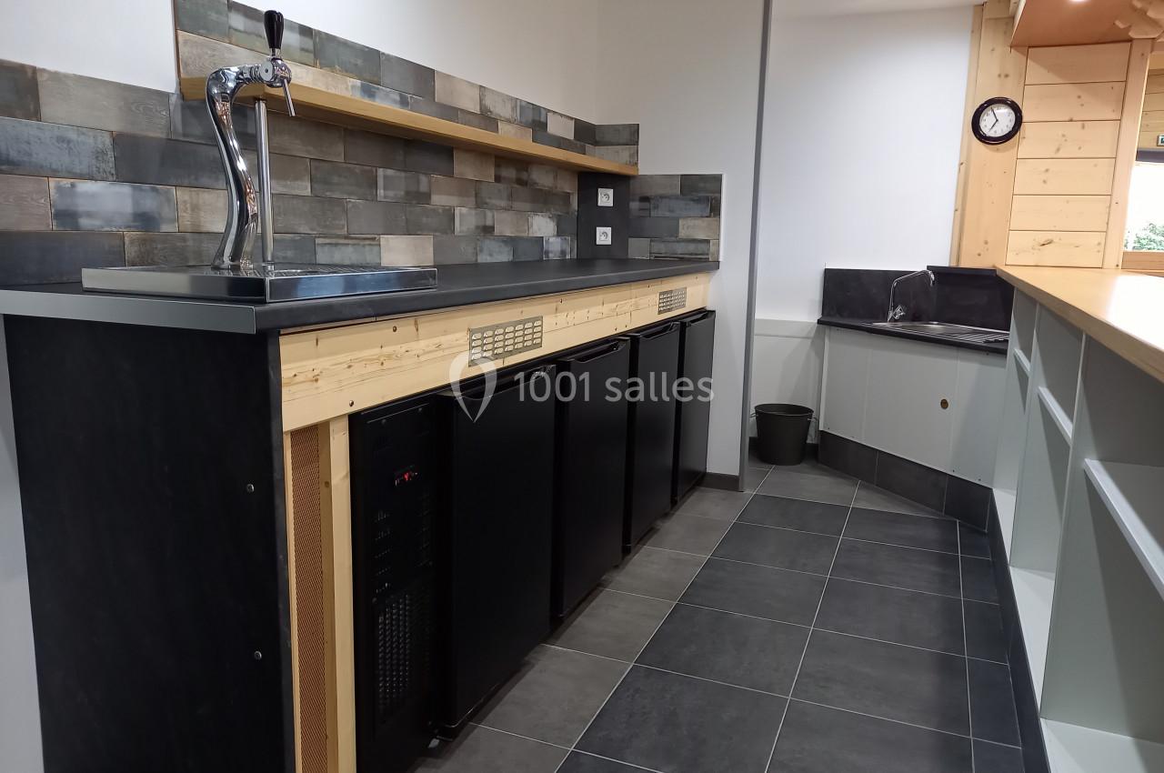 Comptoir de bar moderne avec réfrigérateurs intégrés, robinet à bière, crédence en carreaux et évier en arrière-plan.