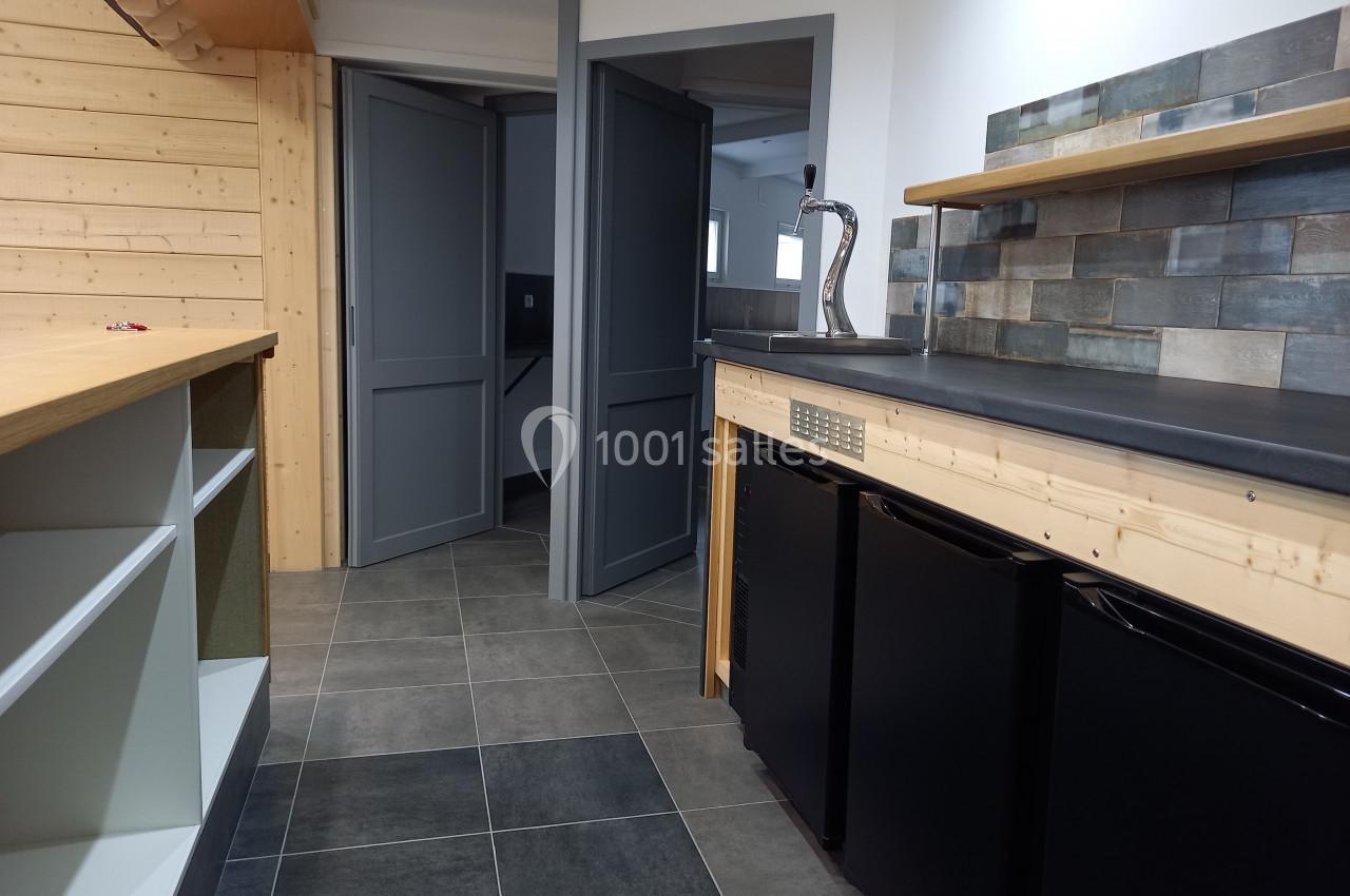 Cuisine moderne avec plan de travail en bois, crédence en carreaux et petits réfrigérateurs noirs intégrés.