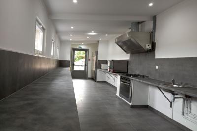 Paysage rural avec une ferme traditionnelle entourée de champs verdoyants et d'arbres sous un ciel nuageux.