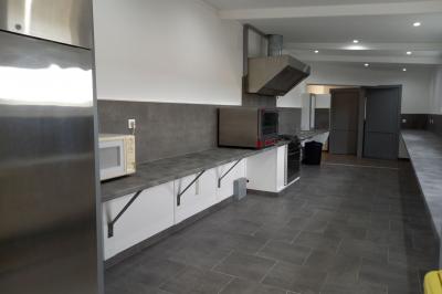 Paysage rural avec une ferme traditionnelle entourée de champs verdoyants et d'arbres sous un ciel nuageux.