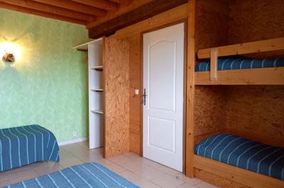 Paysage rural avec une ferme traditionnelle entourée de champs verdoyants et d'arbres sous un ciel nuageux.