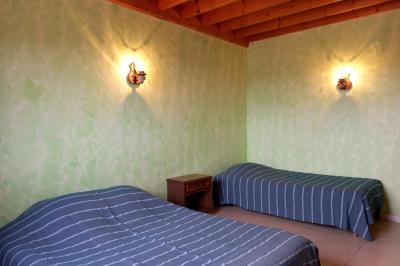 Paysage rural avec une ferme traditionnelle entourée de champs verdoyants et d'arbres sous un ciel nuageux.