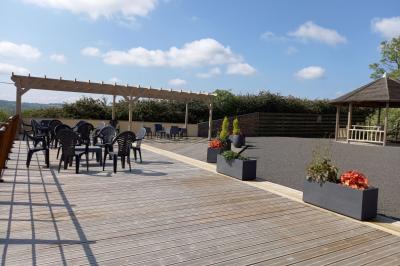 Paysage rural avec une ferme traditionnelle entourée de champs verdoyants et d'arbres sous un ciel nuageux.