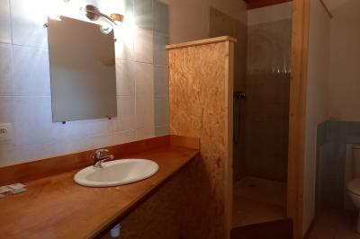 Paysage rural avec une ferme traditionnelle entourée de champs verdoyants et d'arbres sous un ciel nuageux.