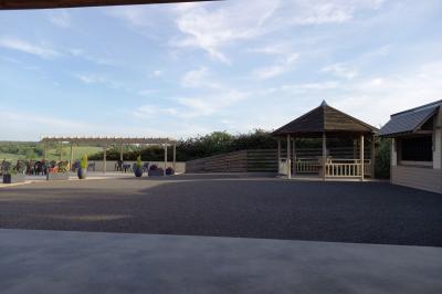 Paysage rural avec une ferme traditionnelle entourée de champs verdoyants et d'arbres sous un ciel nuageux.