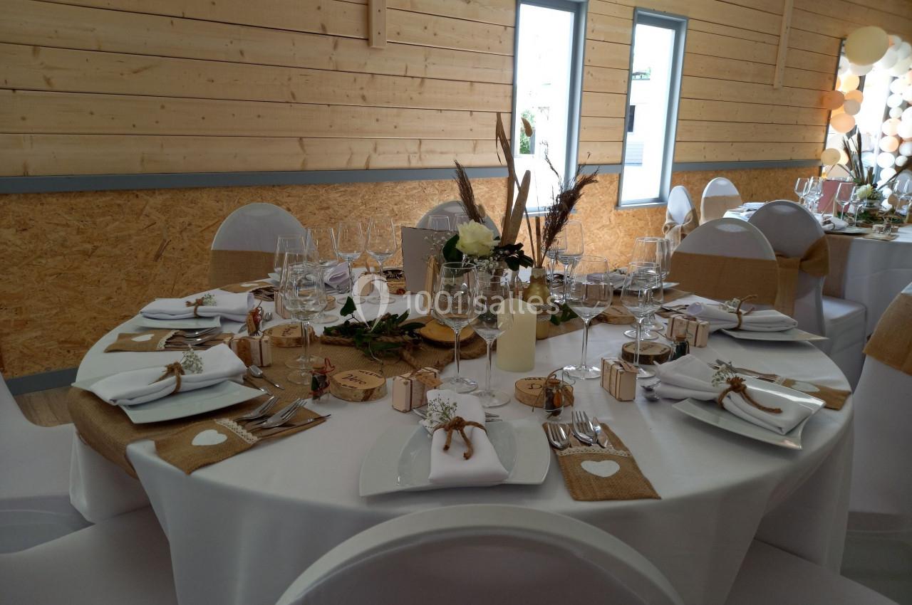 Table de réception décorée avec des éléments naturels, nappes blanches, chemins de table en jute et vaisselle élégante.