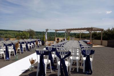 Paysage rural avec une ferme traditionnelle entourée de champs verdoyants et d'arbres sous un ciel nuageux.
