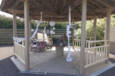 Paysage rural avec une ferme traditionnelle entourée de champs verdoyants et d'arbres sous un ciel nuageux.