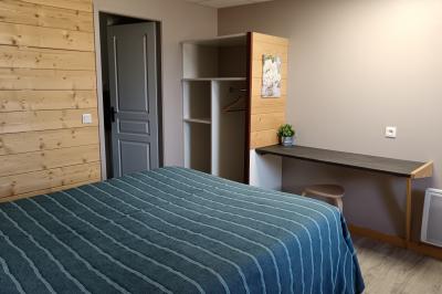 Paysage rural avec une ferme traditionnelle entourée de champs verdoyants et d'arbres sous un ciel nuageux.