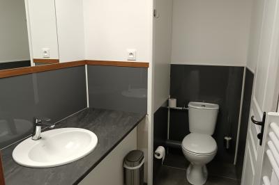 Paysage rural avec une ferme traditionnelle entourée de champs verdoyants et d'arbres sous un ciel nuageux.