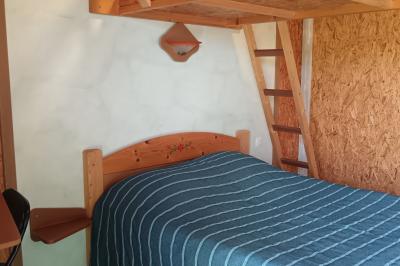 Paysage rural avec une ferme traditionnelle entourée de champs verdoyants et d'arbres sous un ciel nuageux.