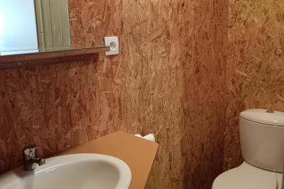 Paysage rural avec une ferme traditionnelle entourée de champs verdoyants et d'arbres sous un ciel nuageux.