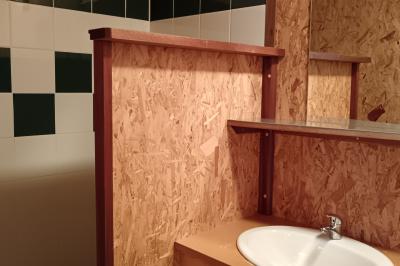 Paysage rural avec une ferme traditionnelle entourée de champs verdoyants et d'arbres sous un ciel nuageux.